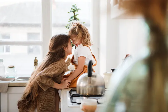 sisters giggling together in kitchen 